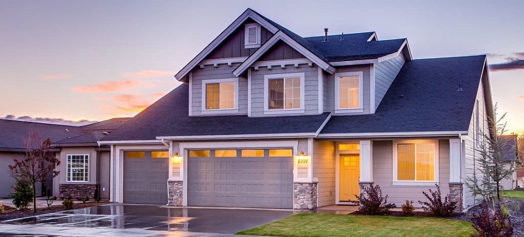 Two-story suburban home with gray siding and three-car garage at sunset